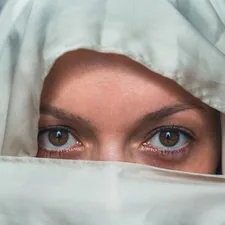 Woman's eyes peek through white fabric with graffiti background related to White Eyelet Valances