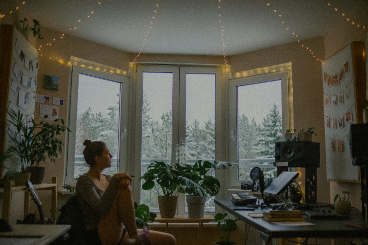 Woman sitting by window with snowy trees outside related to Spruce Up Your Space with Lush Turquoise Window Valances