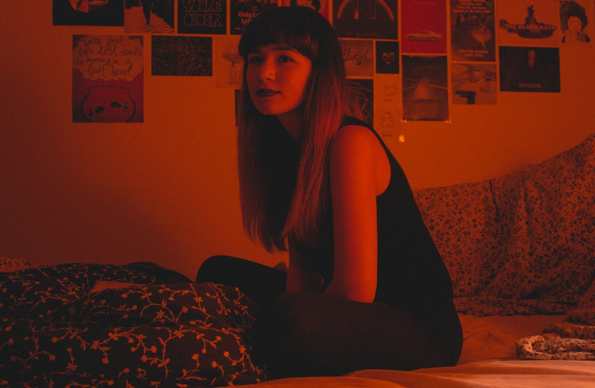 Woman sitting in bed near posters of movies with a red light. related to The Hidden Horror of Red Bed Bugs