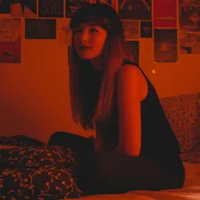 Woman sitting in bed near posters of movies with a red light. related to The Hidden Horror of Red Bed Bugs