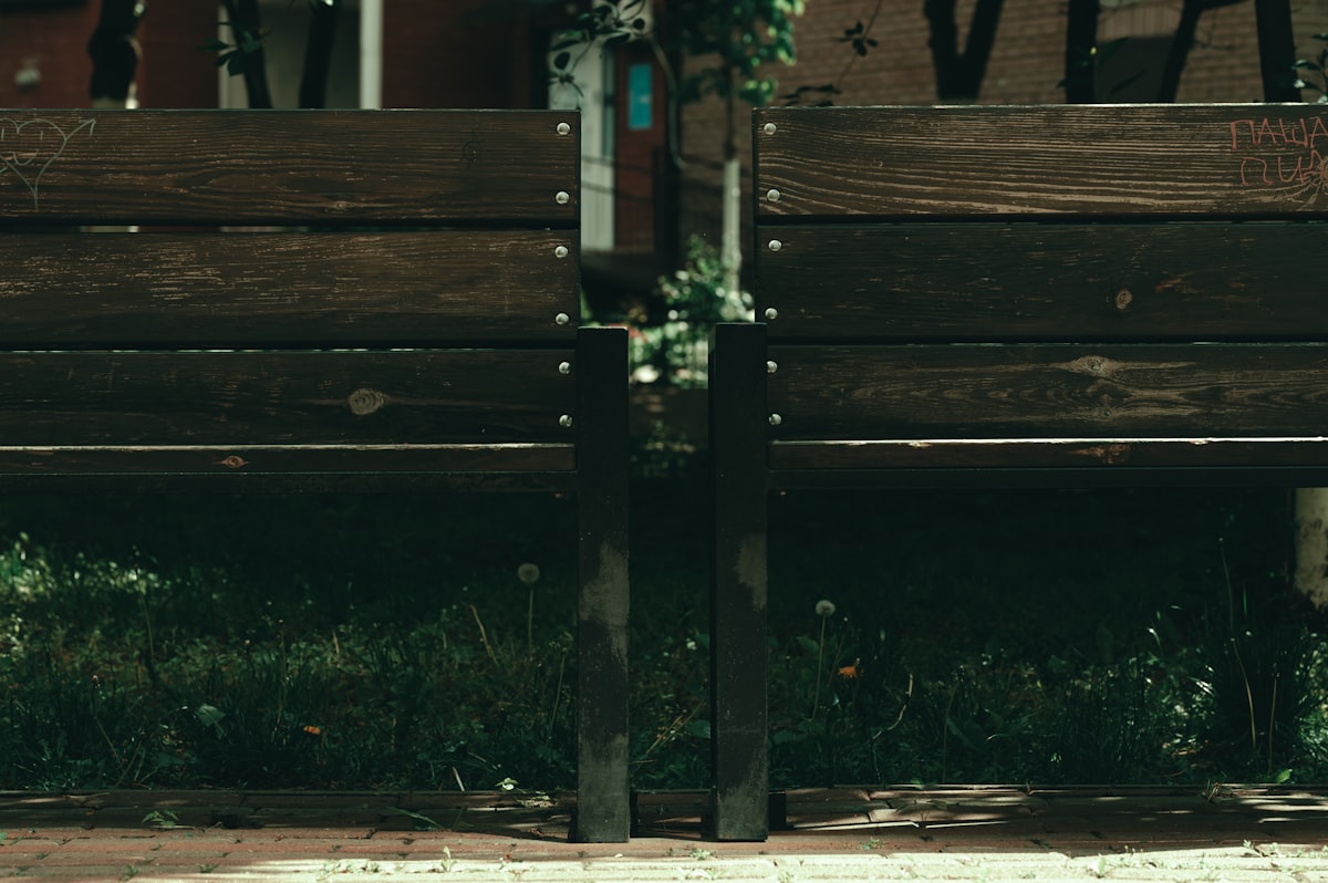 Wooden park bench with green grass and leaves related to Safeguarding Your Outdoor Space: The Importance of Chiminea Spark Arrestors