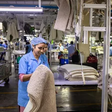 Workers are in a textile factory, manufacturing rugs. related to Navigating the World Market: Bed Bath & Beyond's Journey in Global Retail