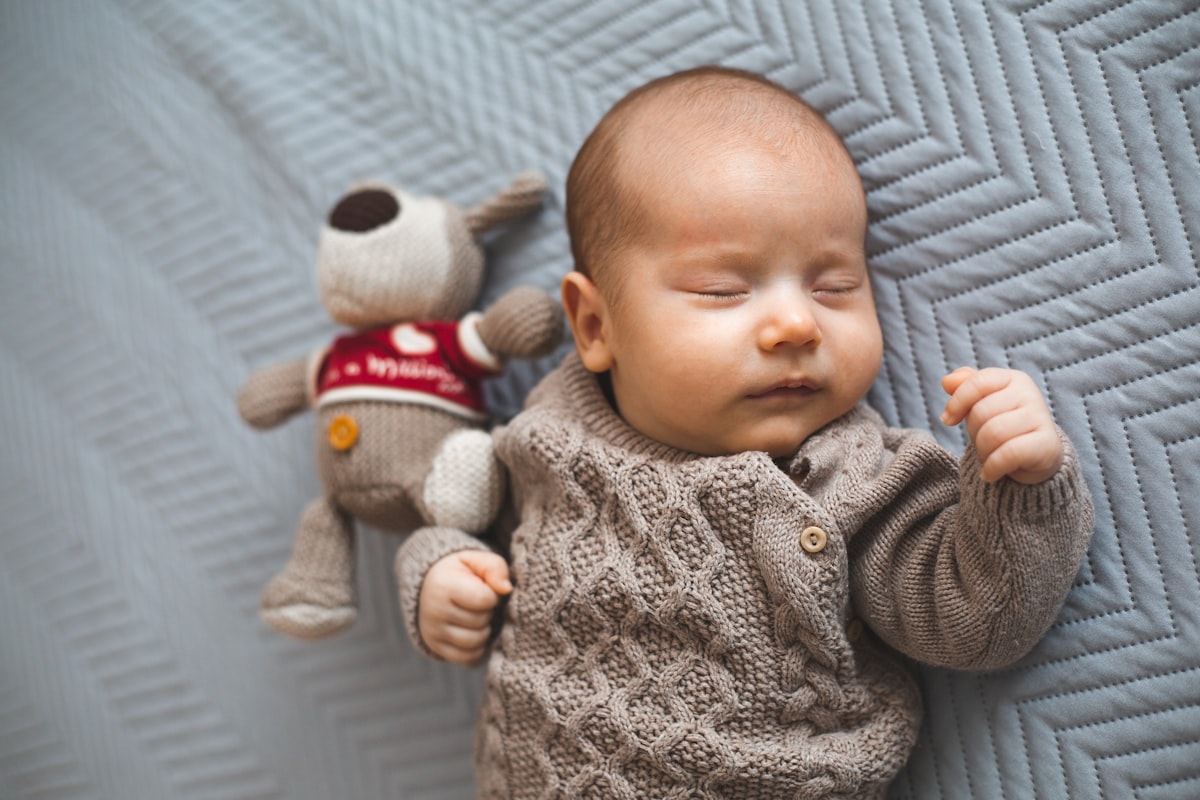 Young baby boy sleeping next to a toy. related to Cozy Comfort for Little Dreamers: Explore the Best IKEA Children's Beds