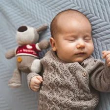 Young baby boy sleeping next to a toy. related to Cozy Comfort for Little Dreamers: Explore the Best IKEA Children's Beds