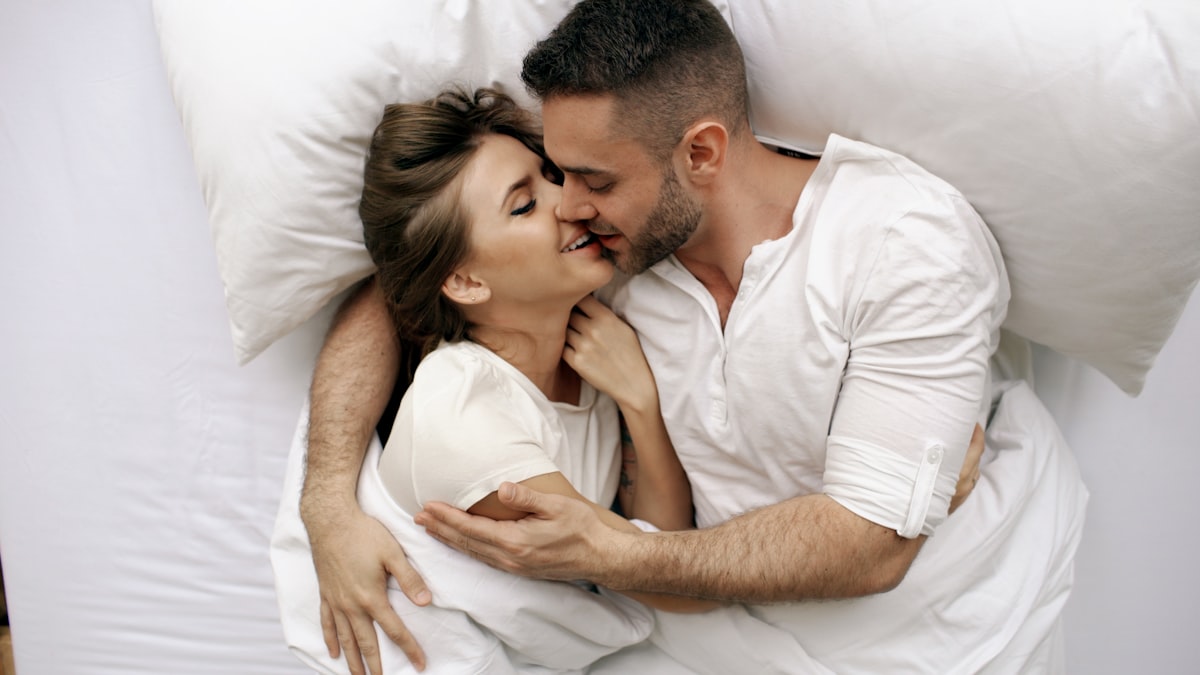 Young beautiful and loving couple kiss and hug into bed while waking up in the morning. related to Unlocking Pleasure: What Men Love in Bed