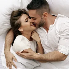 Young beautiful and loving couple kiss and hug into bed while waking up in the morning. related to Unlocking Pleasure: What Men Love in Bed