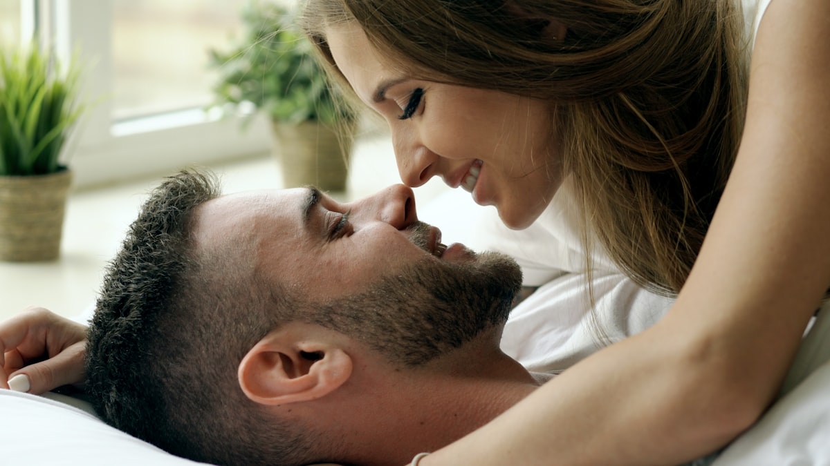 Young beautiful and loving couple wake up at morning. Attractive man kiss and hug his wife in bed related to Exploring the Differences: Men and Women in Bed