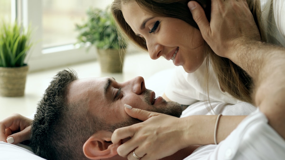 Young beautiful and loving couple wake up at morning. Attractive man kiss and hug his wife in bed related to Unraveling the Mysteries: What Women Like in Bed