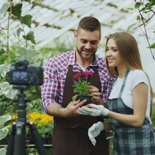 Young smiling blogger couple florist in apron holding flower talking and recording video blog for online vlog about the gardening related to Transform Your Yard with DIY Garden Beds