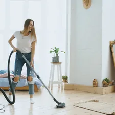 Young woman having fun cleaning house with vacuum cleaner dancing and singing related to The Ultimate Guide to Bed Bath and Beyond Vacuum Cleaners